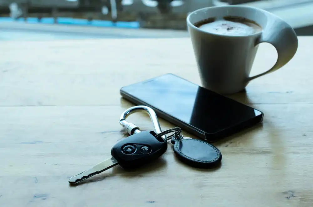 Bakje koffie, telefoon en autosleutels op tafel